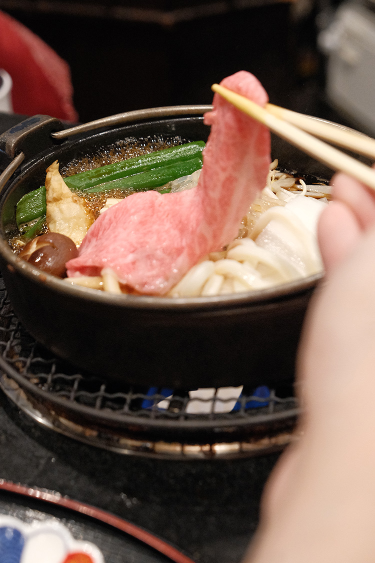 大阪老字號壽喜燒しゃぶ長,一片非常美味的A5黑毛和牛正準備放入壽喜燒中煮。